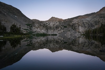 白天在水体旁边有一座绿色和棕色的山